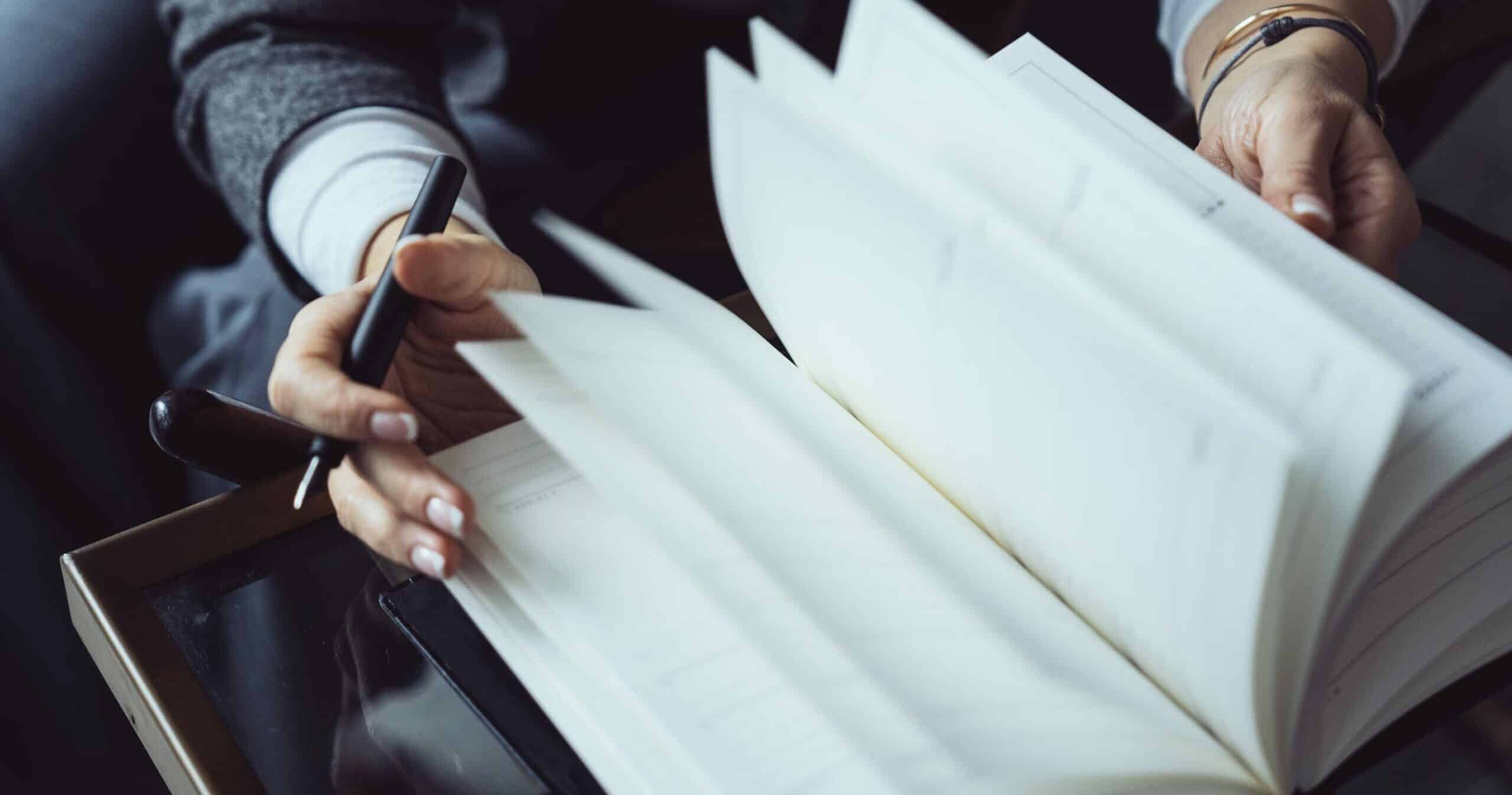 Detail of a woman's hands flipping through a TIMEMASTER notebook.